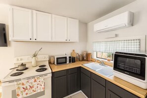 A kitchen with a stove, microwave, oven, sink, and white cabinets. - Hot tub lake wine Cottage State Park 4 mins away (Kelseyville)