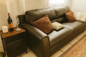 A brown leather sofa with two pillows, a glass of wine, and a bottle of wine on a wooden side table. - Hot tub lake wine Cottage State Park 4 mins away (Kelseyville)