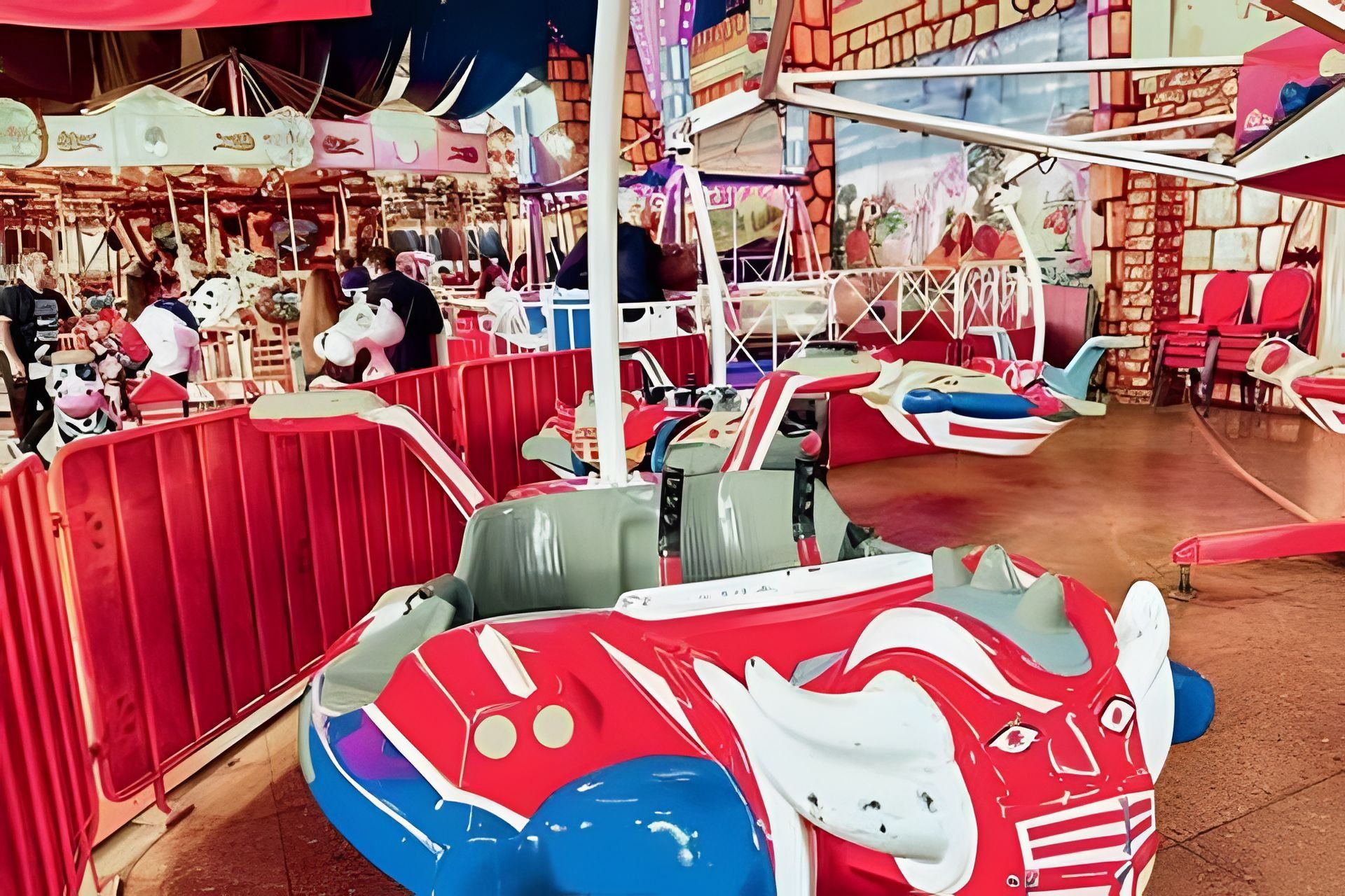 A carousel with colorful seats and a brick wall backdrop.