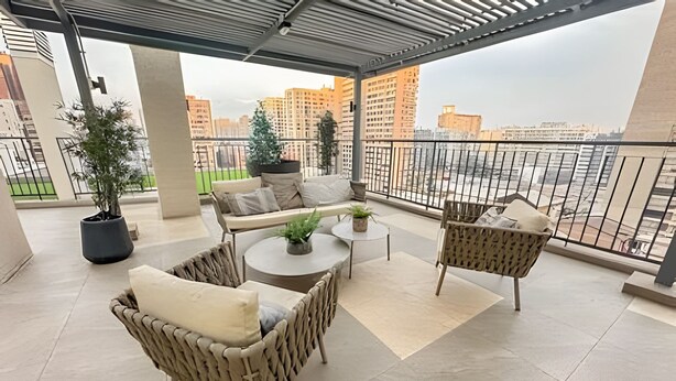 Ein Balkon mit Korbmöbeln, einem kleinen Tisch und Topfpflanzen.