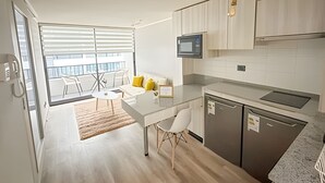 Eine moderne Küche mit Essbereich, einer Mikrowelle und Blick auf einen Balkon.