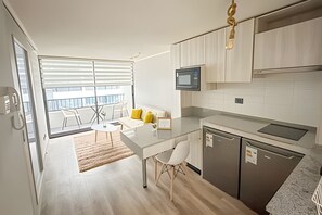A modern kitchen with a dining area, a microwave, and a view to an outdoor balcony. - Depto acogedor cercano a metro y centro (Santiago)