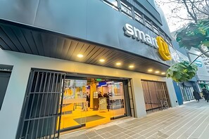 A modern building with a large sign reading 'smart' and a storefront with glass doors. - Depto acogedor cercano a metro y centro (Santiago)
