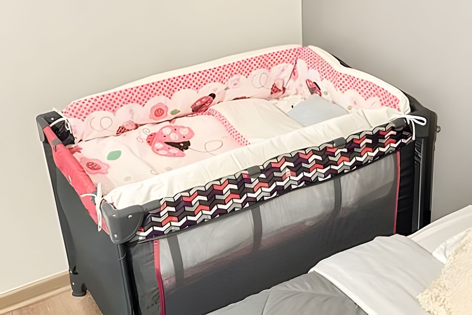 A baby crib with a patterned mattress and a black and red zigzag design on the headboard.