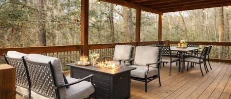 An outdoor deck with wooden flooring, a fire pit, and outdoor furniture.