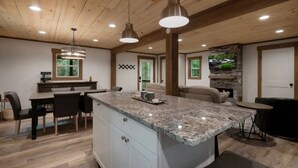 A modern kitchen with granite countertops, wooden ceiling beams, and pendant lighting. - Your Modern Creekside Retreat with Resort Perks! Modern 2bdrm + Open LoftTrundle (Ellijay)
