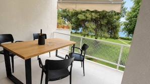 Un balcón con una mesa y sillas de madera, una botella y una planta en maceta.