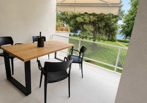 Ein Balkon mit Holztisch und Stühlen, einer Flasche sowie einem Blumentopf.