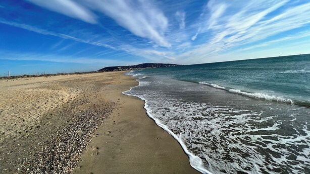 Ein Strand mit klarem Himmel und Wellen.