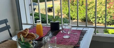 A balcony with breakfast items, a view of the ocean, and a railing.