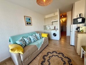 A compact living space with a sofa, a washing machine, a kitchenette, and a dining area. - BEACH FRONT STUDIO WITH TERRACE !!! SUPERB VIEW !!!!! (Sète)