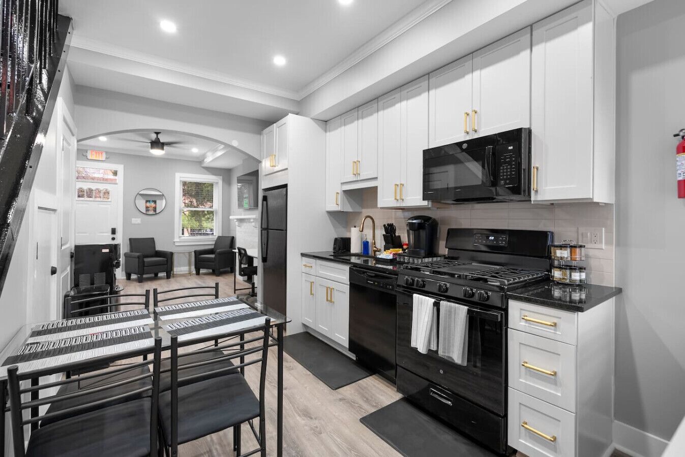 A modern kitchen with white cabinetry, black appliances, and a dining area with a black and white table.