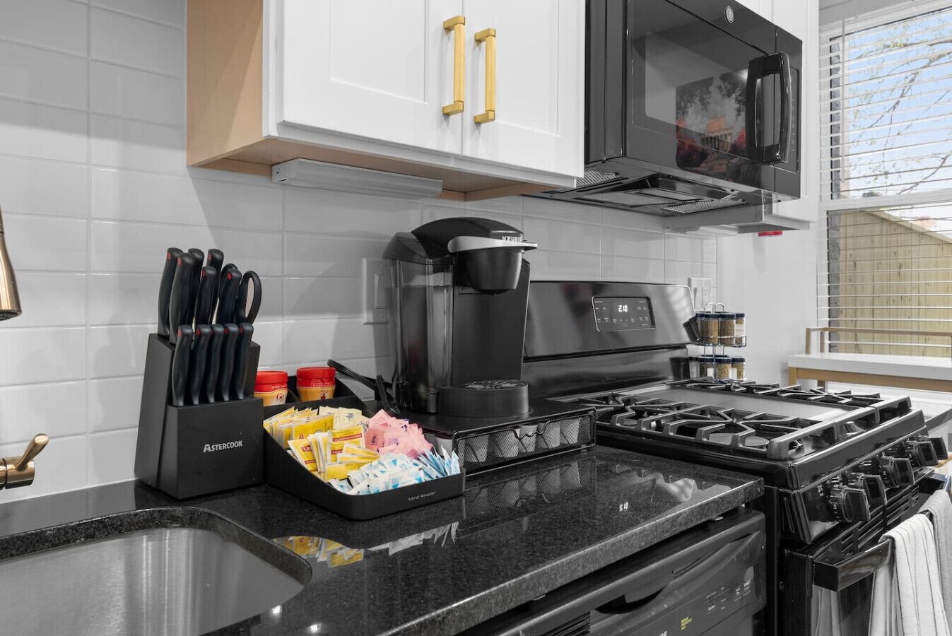 A kitchen with a black stove, a coffee maker, and a knife block.