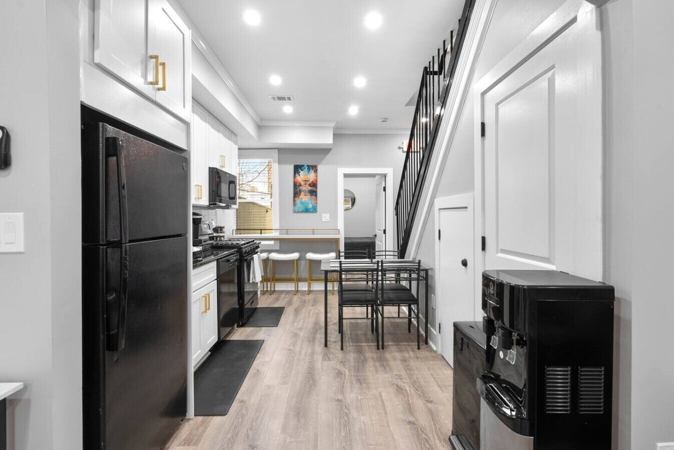 A modern kitchen with a refrigerator, stove, and microwave. There is a dining area with a table and chairs.