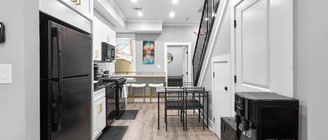 A modern kitchen with a refrigerator, stove, and microwave. There is a dining area with a table and chairs.