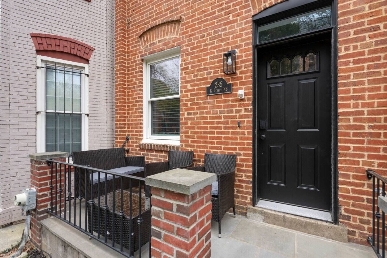 A brick building with a black door, a window with a white frame, and a sign reading '235 K Street NE'.