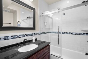 A modern bathroom with a large mirror, a sink, a shower, and a bathtub. - Modern NoMa Retreat | 2BR Near UnionMarket & Metro (Washington)