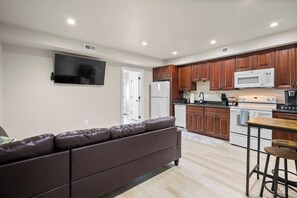 A modern kitchen with wooden cabinets, a white refrigerator, a microwave, and a stove. - Modern NoMa Retreat | 2BR Near UnionMarket & Metro (Washington)