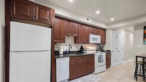 A modern kitchen with wooden cabinets, a white refrigerator, a microwave, a dishwasher, and a stove. - Modern NoMa Retreat | 2BR Near UnionMarket & Metro (Washington)