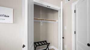 A walk-in closet with a wooden bench, a coat rack, and a door leading to another room. - Modern NoMa Retreat | 2BR Near UnionMarket & Metro (Washington)