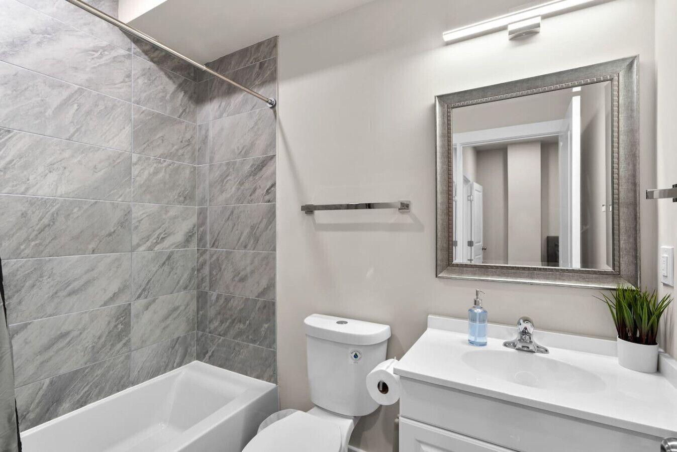 A bathroom with a shower, toilet, sink, and mirror.