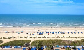 Ein Strand mit Sonnenschirmen, Liegestühlen und freiem Blick auf das Meer.