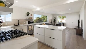 Una cocina moderna con una isla central, electrodomésticos integrados y un comedor con vistas.