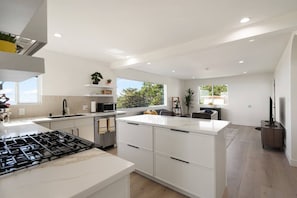 A modern kitchen with a central island, built-in appliances, and a dining area with a view.