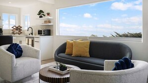 Una sala de estar moderna con un sofá y sillones, una mesita de centro y un ventanal con vistas.