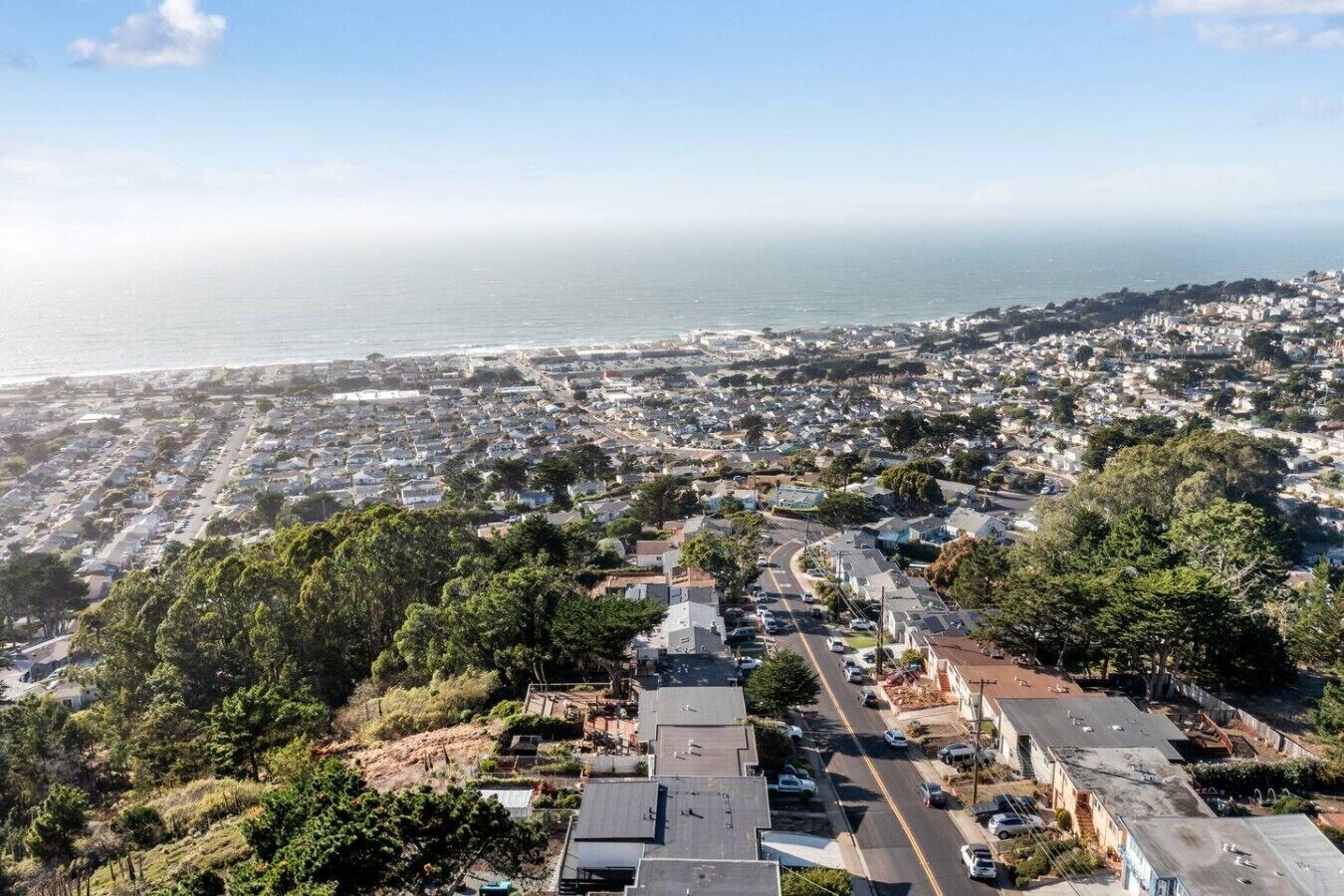 Vista aérea de una zona residencial costera con casas, calles y vista al océano.