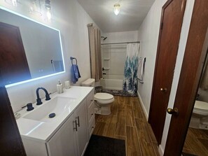 Une salle de bain comprenant un lavabo, des toilettes et un espace douche.