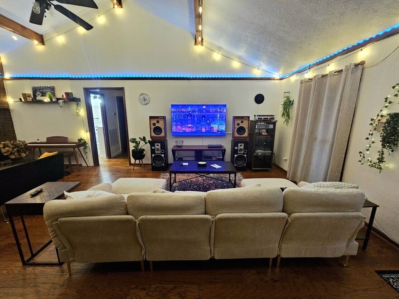 A living room with a sectional sofa, a coffee table, a TV, and two speakers.. The Timber & Tune Retreat: 3BR Woodland Oasis | Huge Rolling Yard | 15 Min to Ryman