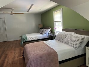 A bedroom with two beds, a ceiling fan, a window with blinds, and a nightstand with a lamp. - Lovely 4-bedroom house in Teaneck - 3 mins walk to bus, 20 mins drive NYC. (Teaneck)