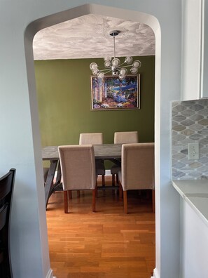 A dining area with a wooden table and chairs, a ceiling fan, and a painting on the wall. - Lovely 4-bedroom house in Teaneck - 3 mins walk to bus, 20 mins drive NYC. (Teaneck)