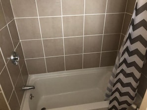 A bathroom with a bathtub, tiled walls, and a shower curtain. - BEACHWAY MOTEL (Salisbury)
