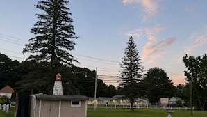 A small wooden building with a red roof, possibly a lighthouse, surrounded by grass and trees. - BEACHWAY MOTEL (Salisbury)