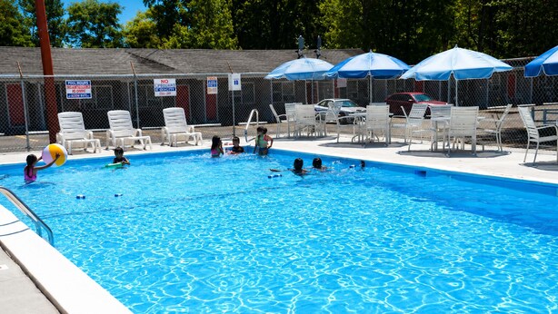 A swimming pool with a fenced area, lounge chairs, and umbrellas. - BEACHWAY MOTEL (Salisbury)