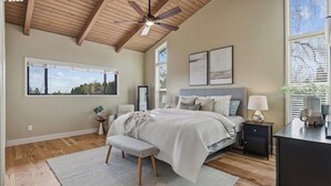 Une chambre à coucher comprenant un lit, un banc, un bureau, un ventilateur de plafond et une fenêtre.