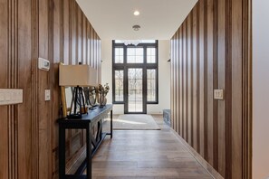 Ein Korridor mit Holzwandverkleidung, einer Bank mit Lampe und einem großen Fenster am Ende.