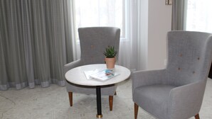 Um quarto com duas poltronas cinzas, uma mesa redonda com tampo branco e um vaso de planta sobre a mesa.