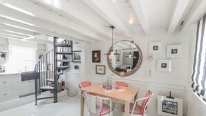 A spacious kitchen with white cabinets, a wooden dining table, and a spiral staircase. - .3 Miles from MacMillan Pier with Parking! (Provincetown)