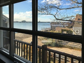 Ein Fenster mit Blick auf einen Wasserblick, eine Holzterrasse und ein Gebäude mit schrägem Dach.