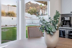 A kitchen with a coffee maker, a potted plant, and a view of a landscaped garden. - Prime Location5BR+DivingPool+Spa+GameRoom+PuttingG (Phoenix)