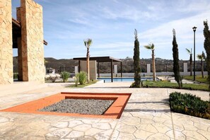 Un bâtiment en pierre avec une piscine, des palmiers et un ciel dégagé.