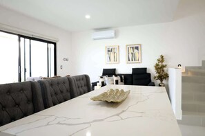 Un interno moderno con un tavolo in marmo, sedute rivestite in grigio e opere d'arte alle pareti.