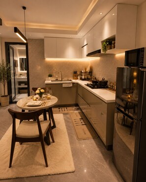 A modern kitchen with a dining area, featuring a round table, chairs, a refrigerator, and a microwave.