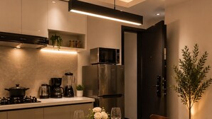 A modern kitchen with a dining area, including a round table set for two, a coffee maker, and a refrigerator. - 1 bedroom syokimau near airport with Nairobi national park view. (Nairobi)
