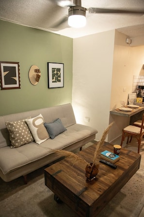 Un salon avec un canapé, une table basse et des œuvres d’art murales.