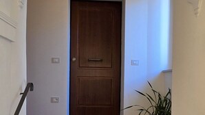 Een houten deur met een hendel, een lichtschakelaar en een stopcontact op de muur.