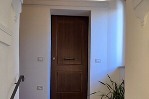 A wooden door with a handle, a light switch, and a power outlet on the wall. - Ancient Convent - Casoni House (Recanati)